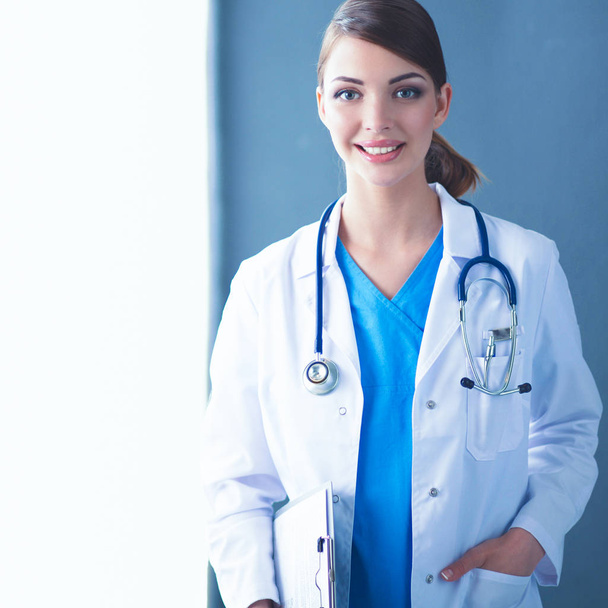 Young doctor or medic with clipboard and stethoscope isolated on grey background - Foto, Bild