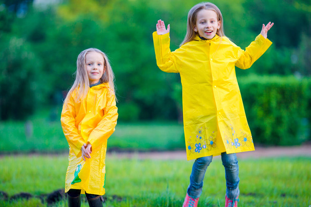 Adorabile bambine che indossano cappotto impermeabile divertirsi all'aperto
 - Foto, immagini