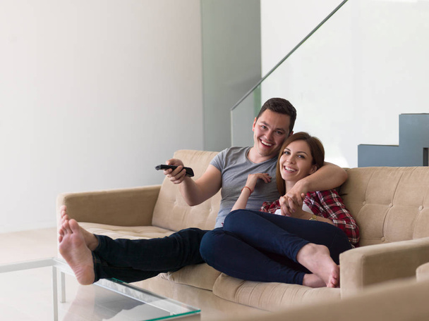 Молода пара на дивані дивиться телевізор
 - Фото, зображення