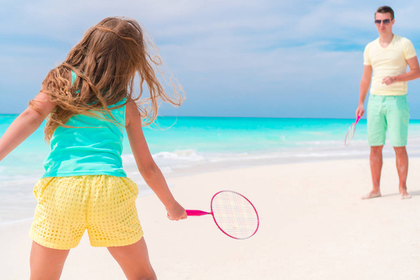 Little girl playing beach tennis on vacation with dad - Photo, Image