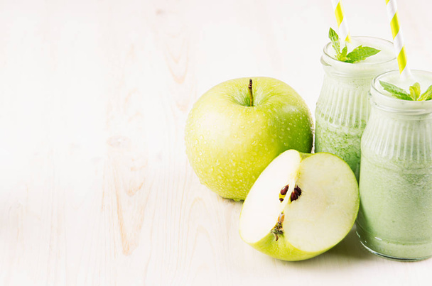 Green apple fruit smoothie in glass jars with straw, mint leaves, apples. White wooden board background, copy space. - Photo, Image