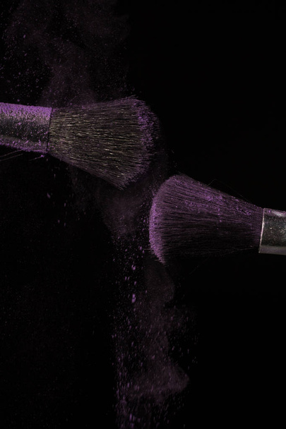Make up brush with purple dust on black background - Foto, Bild