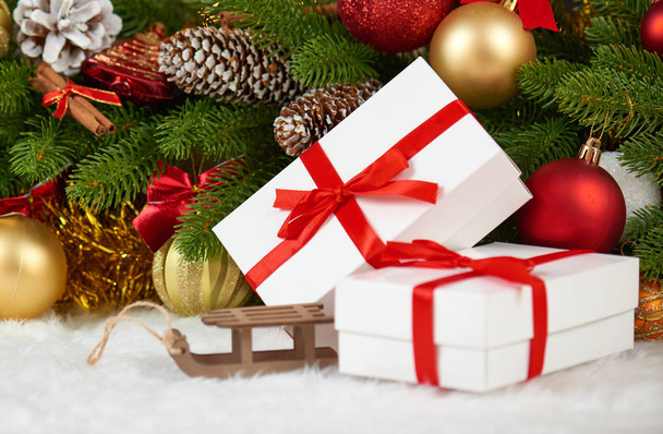 クリスマス デコレーション モミの木支店クローズ アップ、木製そりグッズ、ギフト、クリスマス ボール、コーン、白空白毛皮、休日の概念は、他のオブジェクトをテキストの配置します。 - 写真・画像
