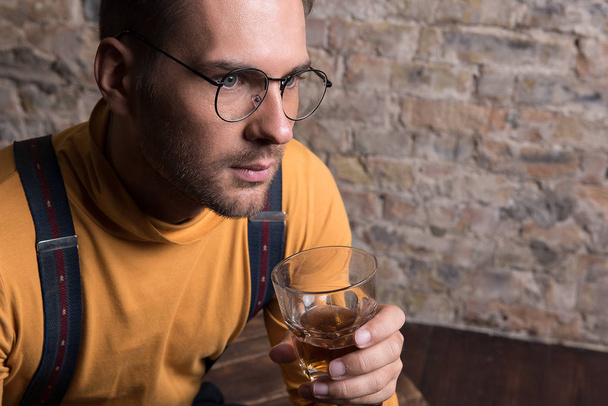 Melancholic youthful man in glasses sorrowfully pondering - Фото, изображение