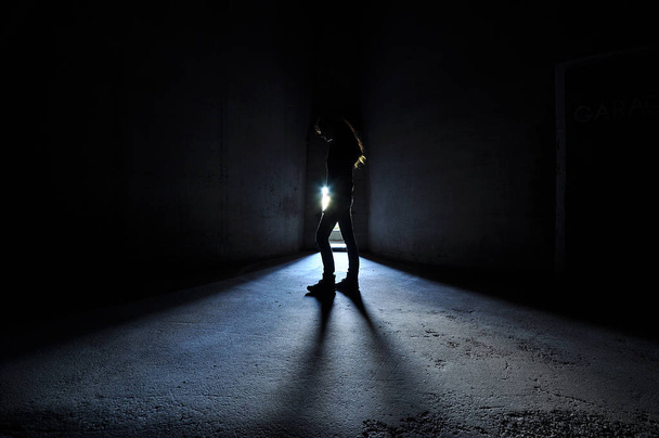 Femme rétro-éclairée debout dans la porte pensant, lumière bleue
. - Photo, image