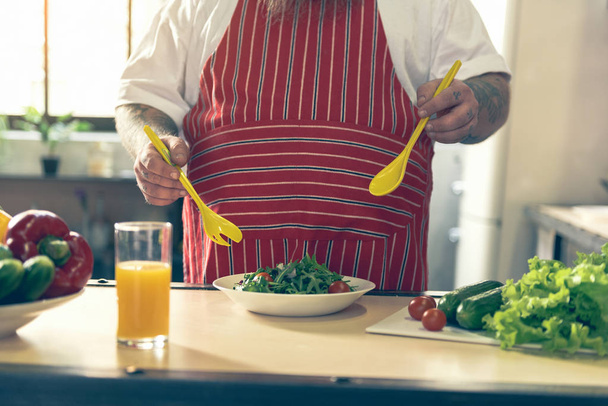 Thick guy mixing salad in kitchen - Fotografie, Obrázek