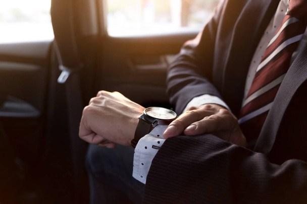 schöner Geschäftsmann schaut auf Armbanduhr im Auto - Foto, Bild