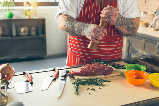 Thick guy peppering meat before cooking - Fotoğraf, Görsel