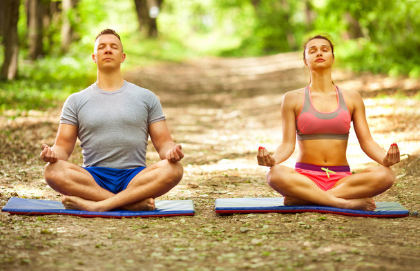 young couple relaxing in yoga pose in green nature - Φωτογραφία, εικόνα
