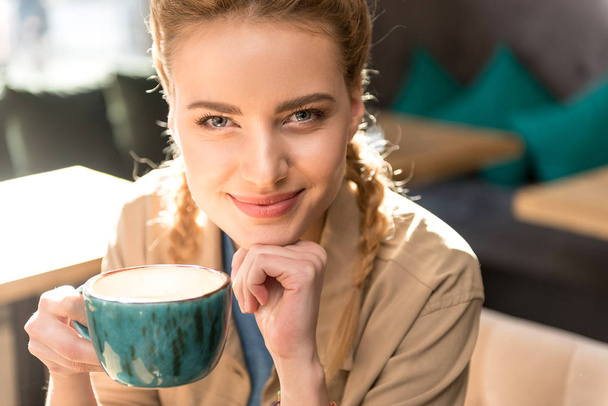 Pensive girl tasting mug of hot beverage - Zdjęcie, obraz