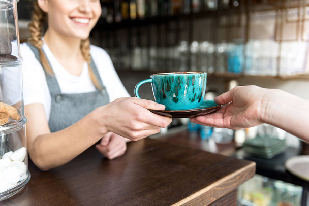 Γυναικείο χέρι δίνει νόστιμο καφέ στον υπολογιστή-πελάτη - Φωτογραφία, εικόνα