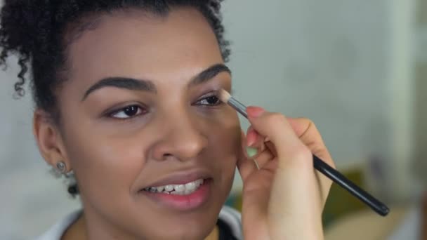 Professional make-up artist makes makeup of afro-american model. Beauty and fashion concept. - Footage, Video