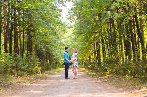 onnellinen nuori raskaana oleva nainen miehensä kanssa kävelee puistossa
 - Valokuva, kuva