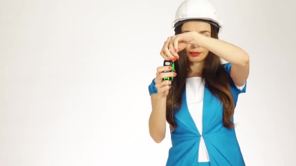 Beautiful female construction engineer or architect in hard hat using measure tape against white background. 4K video - Imágenes, Vídeo
