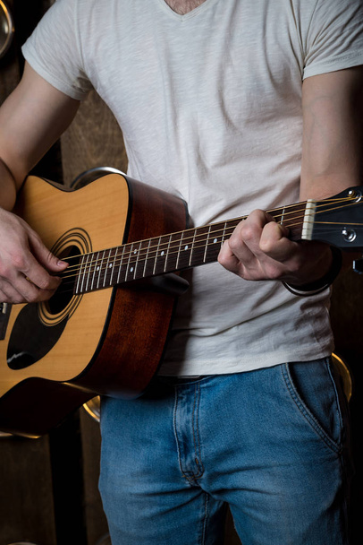 Παίζοντας κιθάρα. Ακουστική κιθάρα στα χέρια του κιθαρίστα. Κατακόρυφο πλαίσιο - Φωτογραφία, εικόνα