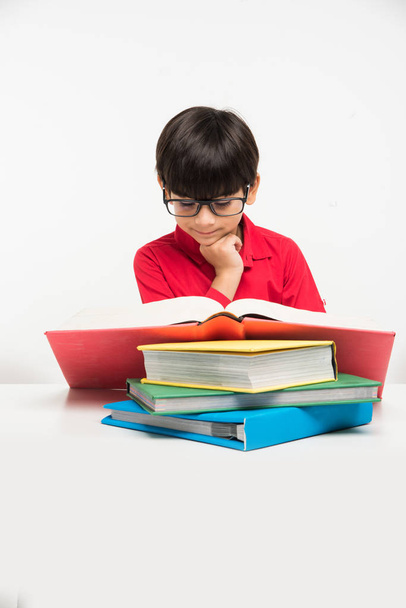 Indiase schattige kleine jongen of jongen leesboek over studielijst, geïsoleerd op witte achtergrond - Foto, afbeelding