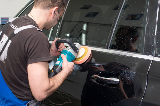 A man polishes a black car with a polishing machine - Photo, Image