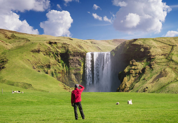 Turista olha para a cachoeira Skogafoss na Islândia
 - Foto, Imagem