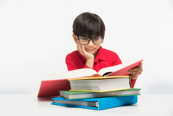 Ινδική χαριτωμένο μικρό αγόρι ή παιδί ανάγνωση βιβλίο πέρα από μελέτη του πίνακα, απομονώνονται σε λευκό φόντο - Φωτογραφία, εικόνα