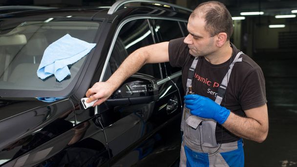 A man polishes a black car with a polishing machine - Foto, Imagem
