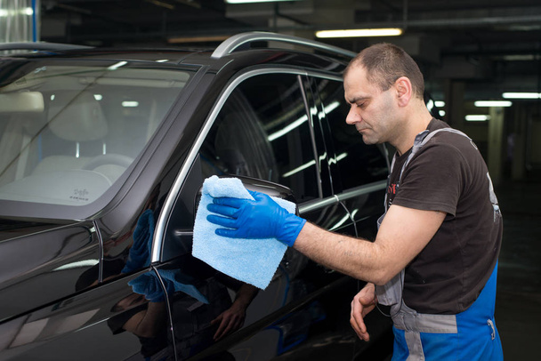 A man polishes a black car with a polishing machine - 写真・画像