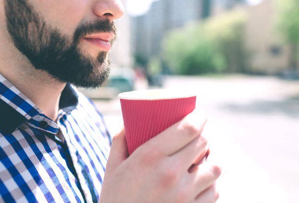 A bearded man enjoys a morning coffee on the street - Foto, afbeelding