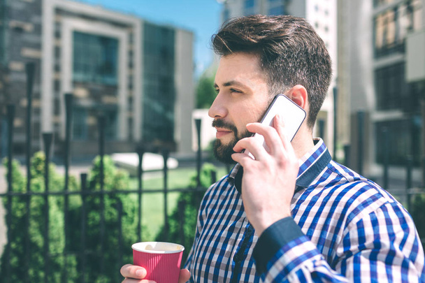Handsome sporty bearded dark-haired man Drinking coffee and talking on the phone - 写真・画像