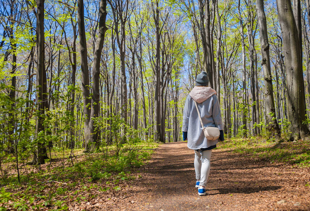 Young woman walking alone in early spring forest - Φωτογραφία, εικόνα
