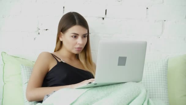 Young woman using her laptop in the bed closeup - Πλάνα, βίντεο