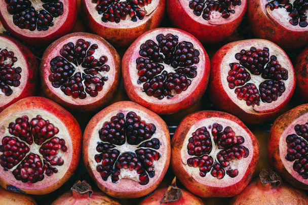 Rows of red juicy ripe sliced pomegranate on the market creating a backgrou - Zdjęcie, obraz