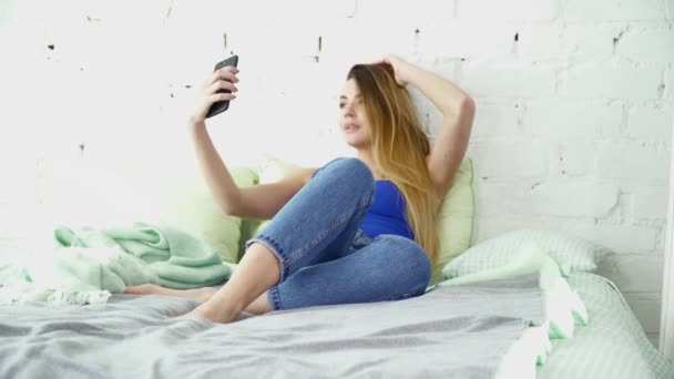 Young beautiful woman making selfie laying in the bed - Materiaali, video