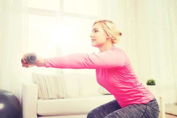 smiling woman with dumbbells exercising at home - Foto, Imagen
