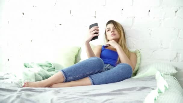 Beautiful woman making selfie laying in the bed closeup - Materiaali, video