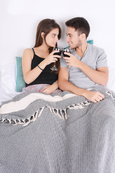 Couple drinking wine in bed. - Фото, изображение