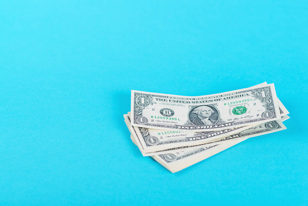 Concept sparen, financiën, economie. Één dollar biljetten geïsoleerd op blauwe backround. - Foto, afbeelding