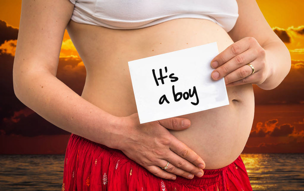 Femme enceinte tenant du papier avec inscription : C'est un garçon
 - Photo, image