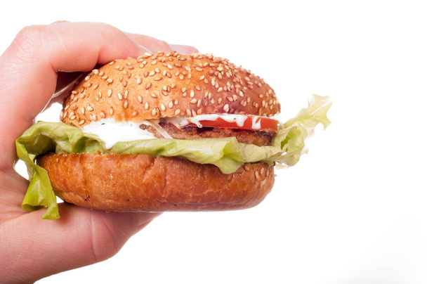 Mão segura hambúrguer fresco. Isolado sobre um fundo branco
 - Foto, Imagem