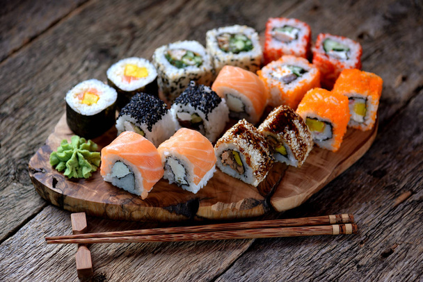 Sushi fatti in casa con salmone, caviale tobiko, frittata, cetriolo, sesamo e formaggio morbido. Stile rustico
. - Foto, immagini
