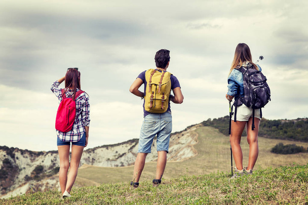 grupo de jóvenes excursionistas caminando hacia el horizonte sobre la montaña
 - Foto, Imagen
