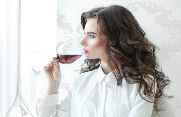 Portrait of beautiful elegant woman with long curly hair drinkin - Photo, image