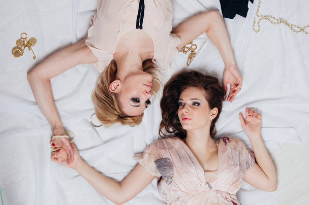 Two girls lie on the floor among accessories - Valokuva, kuva