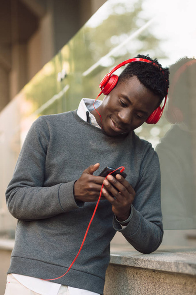 African american man with headphones listen music in city - Foto, Bild
