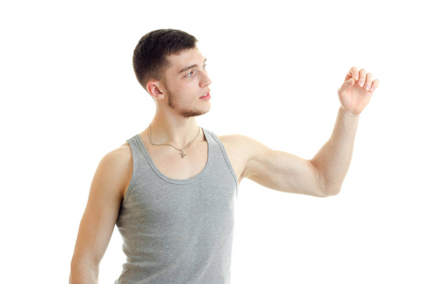 a young guy in the gray shirt looks toward raises his hand and straining muscles - Foto, afbeelding