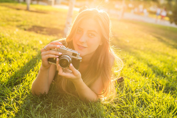 Pretty girl lying on the grass with vintage camera. - Foto, immagini