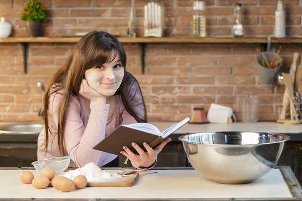Женщина готовит еду на кухне и читает кулинарные рецепты в книге
. - Фото, изображение