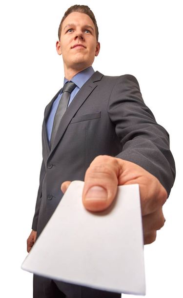 Изолированный молодой привлекательный успешный улыбающийся бизнесмен передает визитную карточку. Снимок под низким углом с копированием
. - Фото, изображение