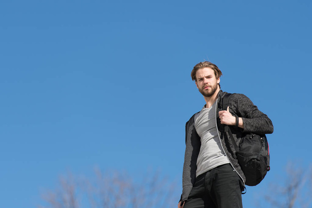 thoughtful young man against blue sky background with sport bag - 写真・画像