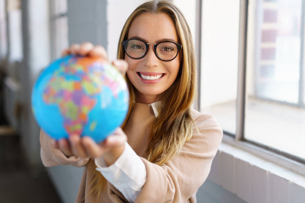 Smiling happy businesswoman holding up a globe - Fotoğraf, Görsel