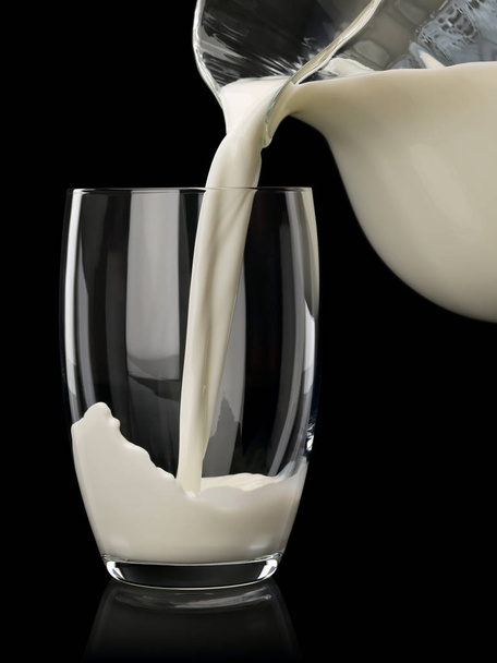 Filling of a glass by milk from a glass jug - Foto, imagen