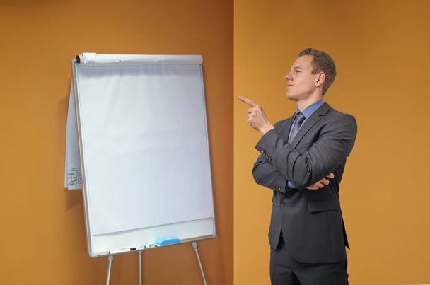 Молодий бізнесмен вказує пальцем на фліп-чарт в офісі - ізольовано з копійкою. Скептичний, критичний або аналітичний вираз для реклами
. - Фото, зображення